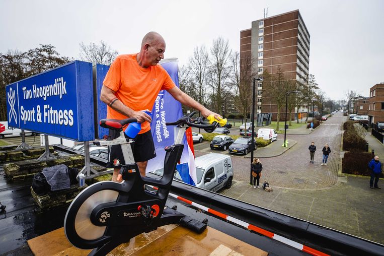 Een deelnemer desinfecteert de spinfiets na een les op het dak van sportschool Tino Hoogendijk Sport & Fitness. Beeld ANP